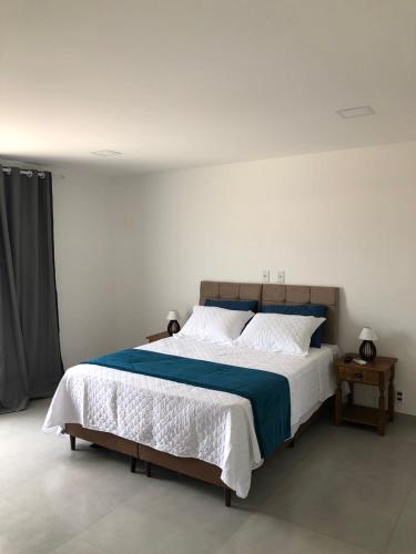a bedroom with a large bed with blue and white sheets at Pousada Litorânea in Saquarema