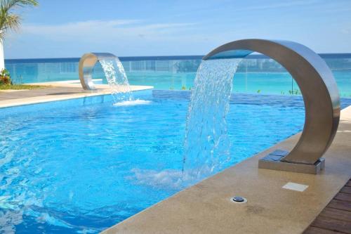 a swimming pool with two water fountains in a resort at Estudio 1A sobre hermosa playa, excelente opción in Cancún