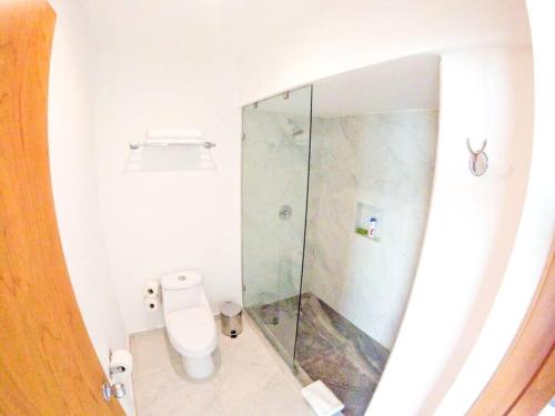 a bathroom with a toilet and a glass shower at Estudio 1A sobre hermosa playa, excelente opción in Cancún