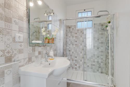 een witte badkamer met een wastafel en een douche bij Casa D`Avó Celina in Funchal