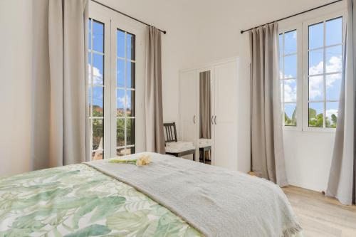 a white bedroom with a bed and large windows at Casa D`Avó Celina in Funchal