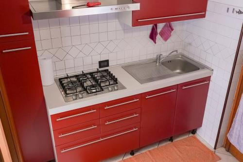 a red kitchen with a stove and a sink at [Elegant Apartment] in Bergamo Center in Bergamo