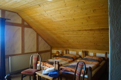 two beds in a room with wooden ceilings at Restaurant Pension-Anton in Jáchymov