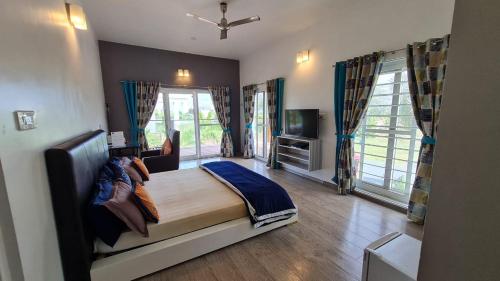 a bedroom with a bed and a tv and windows at 154 Pearl Beach in Mahabalipuram