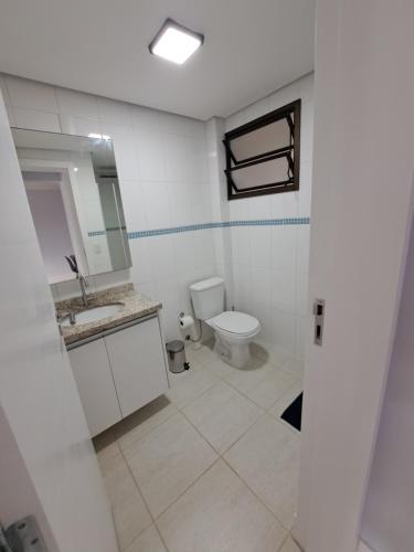 uma casa de banho com um WC, um lavatório e um espelho. em Residence Portal do Santinho em Florianópolis