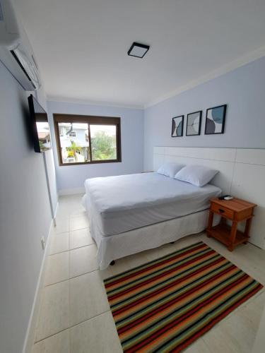 um quarto com uma cama branca e um tapete em Residence Portal do Santinho em Florianópolis