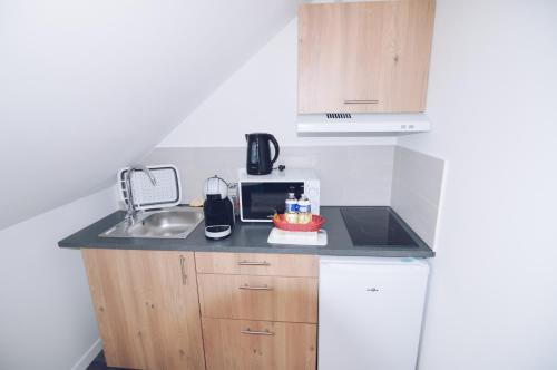 a small kitchen with a sink and a microwave at Studios Lsquare Residence AFPA in Châtellerault