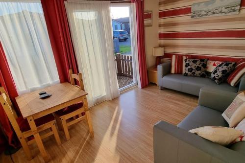 a living room with a couch and a table at Ecky-Thump pet friendly holiday chalet in Bridlington