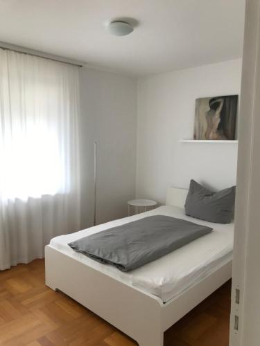 1 cama blanca en un dormitorio blanco con ventana en East View en Freudenstadt
