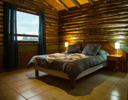 a bedroom with a bed in a log cabin at Cabañas Mirador Azul, Potrerillos in Potrerillos