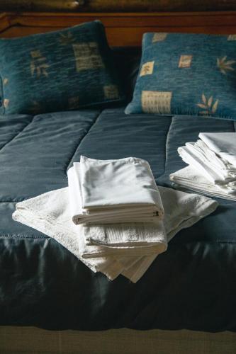 a bed with a pile of towels and books on it at Cabañas Mirador Azul, Potrerillos in Potrerillos