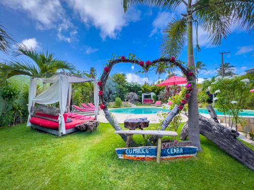 a garden with a swing and a pool at Xainã Pousada de Charme in Cumbuco