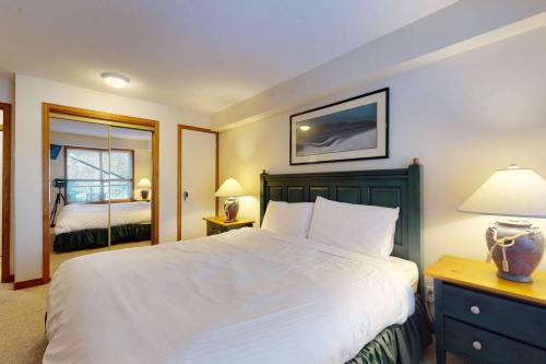 a bedroom with a large white bed and a mirror at Aspens by WB Vacation Rentals in Whistler