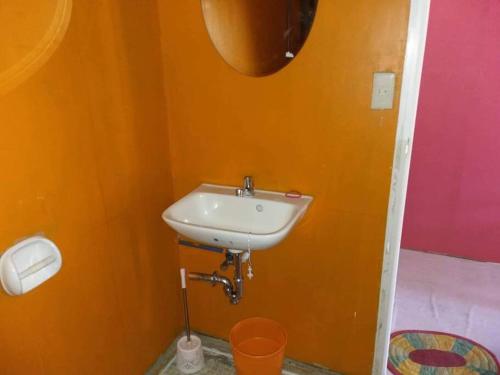 a bathroom with a white sink in an orange wall at Bancudo Cabin and Resort in Karasanan