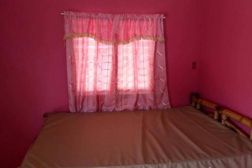 a pink bedroom with a bed with a window at Bancudo Cabin and Resort in Karasanan