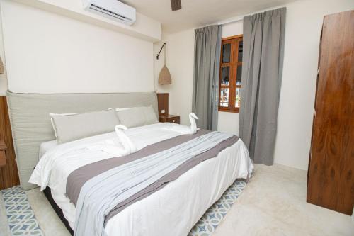 a bedroom with a large white bed with white swans on it at Amaite Holbox - Oceanfront Hotel in Holbox Island