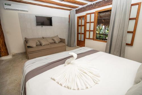 a bedroom with a white bed with a swan on it at Amaite Holbox - Oceanfront Hotel in Holbox Island