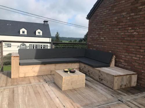 a bench sitting on a patio with a brick wall at Huis met zonneterras, tuin en panoramisch uitzicht in Wellin