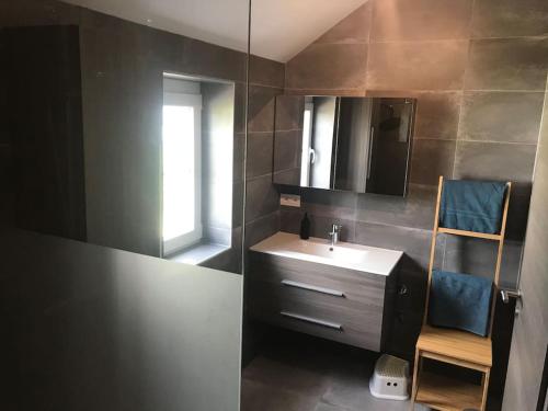 a bathroom with a sink and a mirror and a chair at Huis met zonneterras, tuin en panoramisch uitzicht in Wellin