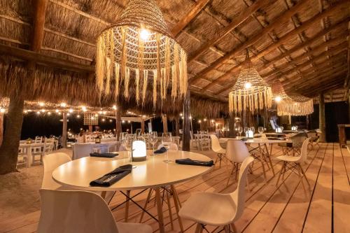 a banquet hall with tables and chairs and chandeliers at Amaite Holbox - Oceanfront Hotel in Holbox Island