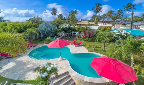 an overhead view of a swimming pool with two red umbrellas at Xainã Pousada de Charme in Cumbuco