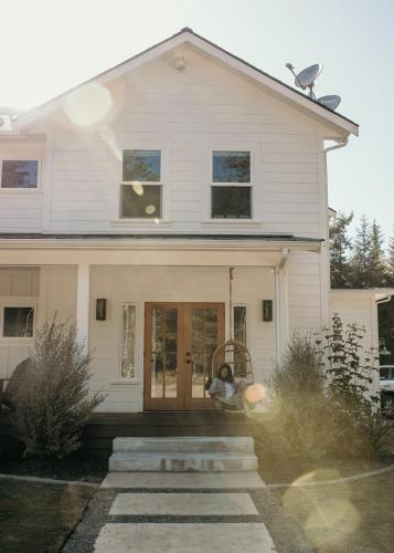 uma casa branca com um cão sentado na porta da frente em Modern Farmhouse Wooded Hide Away em McKinleyville