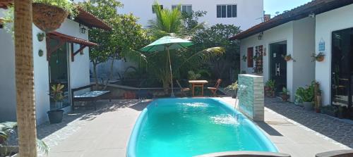 a swimming pool with an umbrella next to a house at FRANCÊS FLATS in Marechal Deodoro