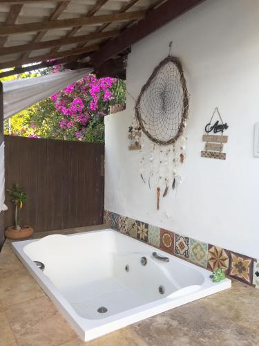 a white bath tub in a room with flowers at Xainã Pousada de Charme in Cumbuco