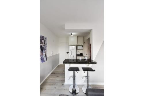 una cocina con paredes blancas y taburetes negros en AAQ309 Studio moderno na Bela Vista, en São Paulo
