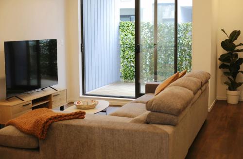 a living room with a couch and a flat screen tv at Cheerful 3-bedroom townhouse close to the city in Auckland