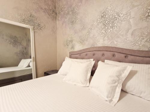 a bedroom with a bed with white pillows and a mirror at Mirvana Apartments Legacy Residence in Timişoara