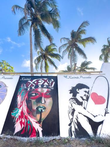 a mural on the side of a building with palm trees at Xainã Pousada de Charme in Cumbuco
