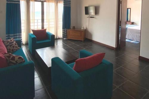 uma sala de estar com duas cadeiras azuis e uma mesa em Reef Bungalow Hotel em Pamunugama