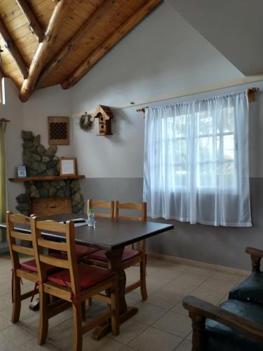 uma sala de jantar com uma mesa e cadeiras e uma janela em Cabañas Pyracantha em Esquel