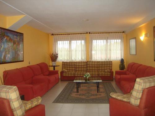a living room with red couches and a table at Hotel Piedra in Perlora
