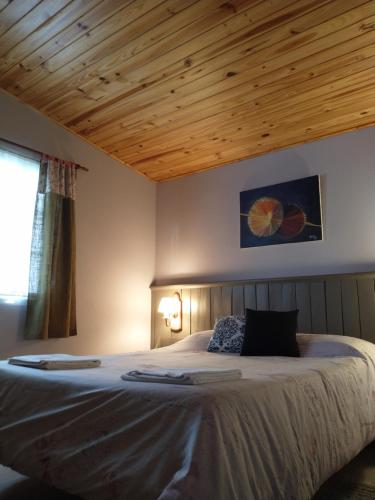 a bedroom with a large bed with a wooden ceiling at Cabañas Pyracantha in Esquel