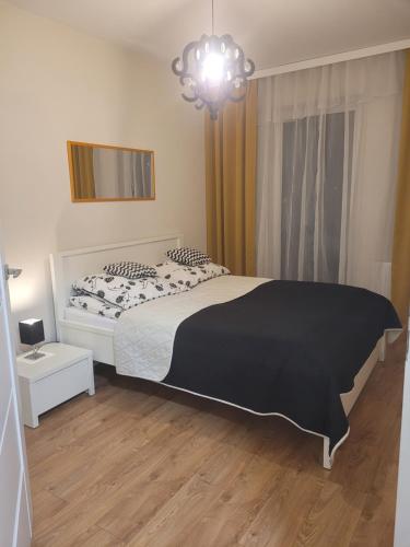 a bedroom with a black and white bed and a chandelier at APARTAMENT-SADOWA in Elblag