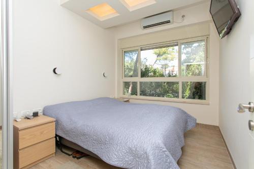 ein Schlafzimmer mit einem Bett und einem Fenster in der Unterkunft Carmel Boutique Apartments - Urban Forest in Haifa