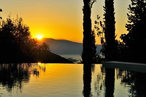 a sunset over a body of water with trees at Mounty Island Villas in Lazaráta