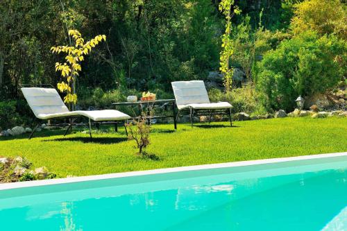 two chairs and a table next to a swimming pool at Mounty Island Villas in Lazaráta