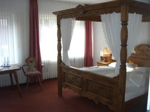 ein Schlafzimmer mit einem Himmelbett, einem Tisch und einem Fenster in der Unterkunft Zur Alten Post in Nottuln