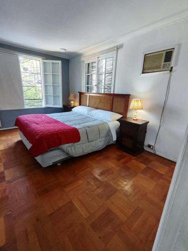 a bedroom with a bed with a red blanket and two windows at HOSTAL SUZI in Santiago