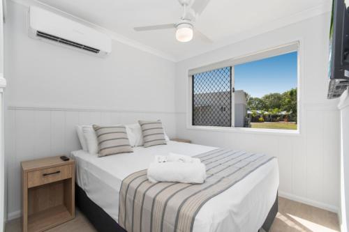a white bedroom with a large bed and a window at Ingenia Holidays Townsville in Townsville