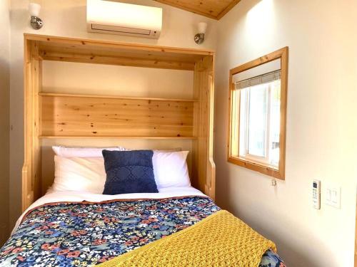 a bedroom with a bed with a wooden headboard and a window at Sunshine Tiny Home Near Downtown SLO in San Luis Obispo