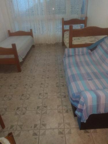 a room with two beds and a tiled floor at Kitinete em Itanhaem in Itanhaém