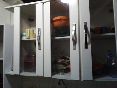 a white cabinet with doors open in a kitchen at Kitinete em Itanhaem in Itanhaém