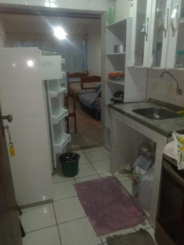 a kitchen with a refrigerator and a sink in it at Kitinete em Itanhaem in Itanhaém