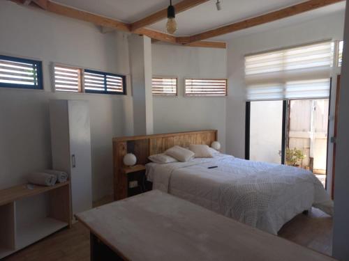 um quarto com uma cama com lençóis brancos e janelas em Hostal CKAIR em Bahia Inglesa