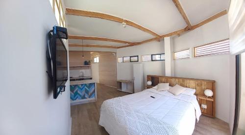 a bedroom with a white bed and a kitchen at Hostal CKAIR in Bahia Inglesa