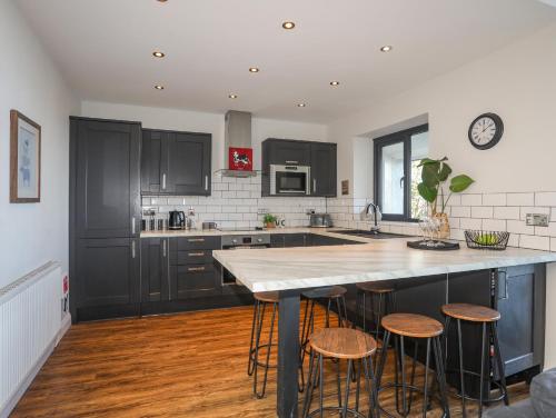 a kitchen with black cabinets and a kitchen island with stools at Haulfryn in Moelfre